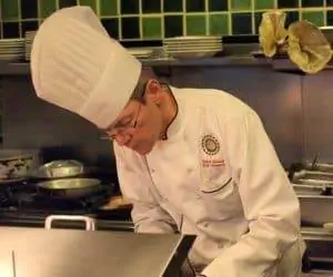 Шеф-повар Роберт Барраль на своей кухне в своем высоком колпаке.