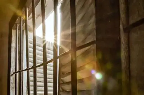 Луч света попадает в бывшую классную комнату, превращенную в тюремную камеру в S-21 в Камбодже.
