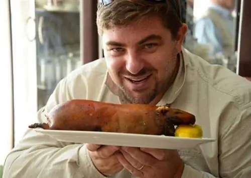 Педро Поркерас наслаждается вкусом свежеприготовленного Куи или морской свинки, сосущей ломтик лимона.