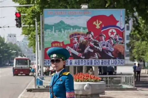 Женщина в форме регулирует движение в Пхеньяне. За ней - один из бесчисленных пропагандистских плакатов, которые повсюду в городе.