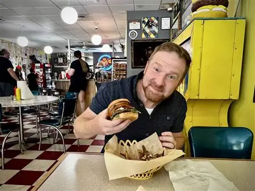 Джон Мартин, житель Биллингса, готовится откусить бургер в The Burger Dive в Биллингсе.