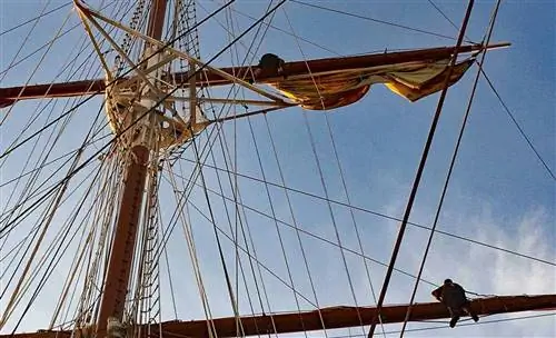 Восемнадцать матросов на Sea Cloud балансируют на такелаже, чтобы вручную установить паруса.