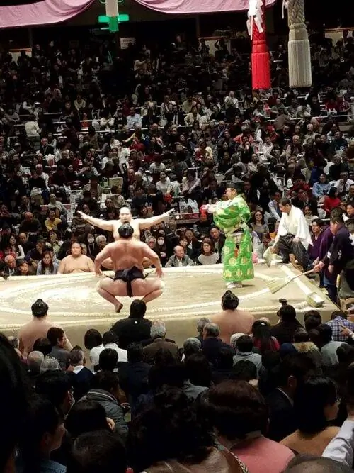 Борцы собираются начать схватку, рядом стоит рефери (гёдзи).