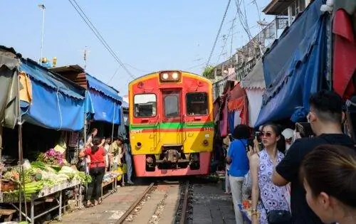 Не пугайтесь, увидев поезда, проходящие мимо рынка в Бангкоке, Таиланд.