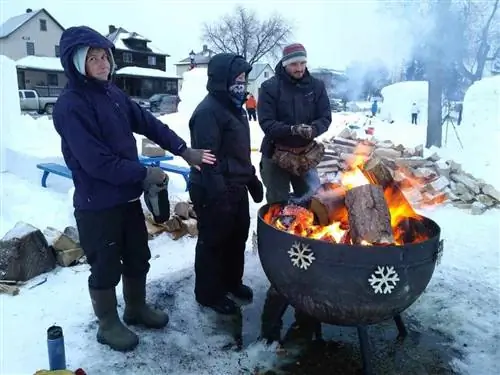 Снежные резчики греют руки во время зимнего фестиваля в Эли.