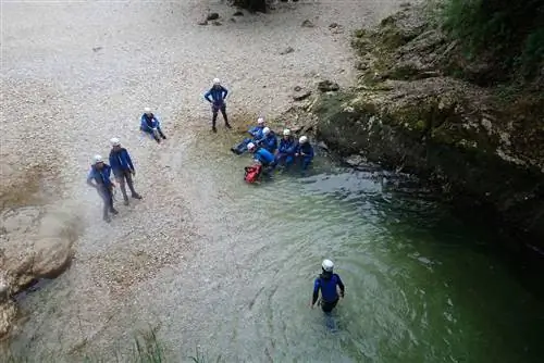 пробираться вброд после финального прыжка с водопада в каньоне в Словении.