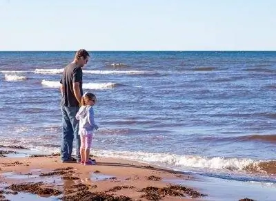 Отец и дочь на пляже в PEI во время фестиваля моллюсков.
