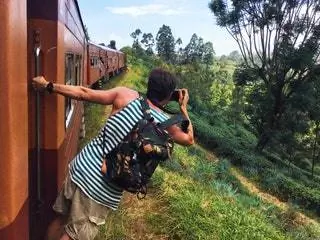 Человек фотографирует из традиционного поезда в Хапутале, Шри-Ланка.