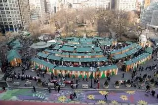 Вид с воздуха на прилавки рождественской ярмарки на Юнион-сквер с зелеными крышами, образующими полукруг.