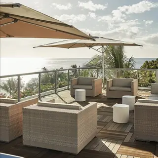 Кафе на террасе с видом на океан и зонтиками над сиденьями в отеле Four Seasons Resort Oahu at Ko Olina.