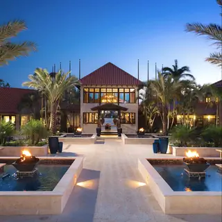 Вход в Sandals Resort на закате с двумя кострищами, зажженными в небольших бассейнах перед главным зданием…