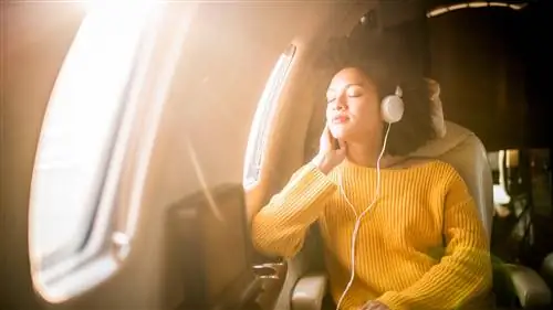 Женщина расслабляется, слушая музыку в самолете.