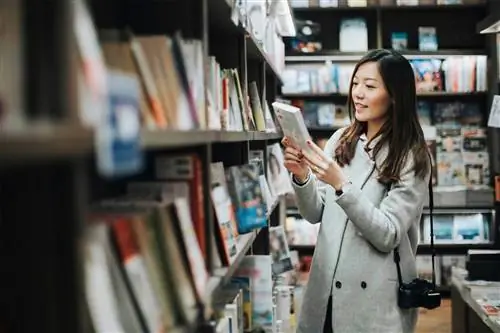 азиатка берет книгу с полки