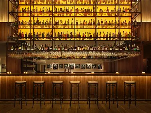 Центральный деревянный бар Bar Veraz с коллекцией бутылок на впечатляющей стальной конструкции, возвышающейся над…
