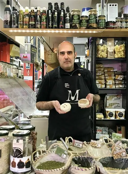 Эрнесто Феррер из продуктового магазина La Sal продает тот же сыр, что и готовит домашний запеченный рис.