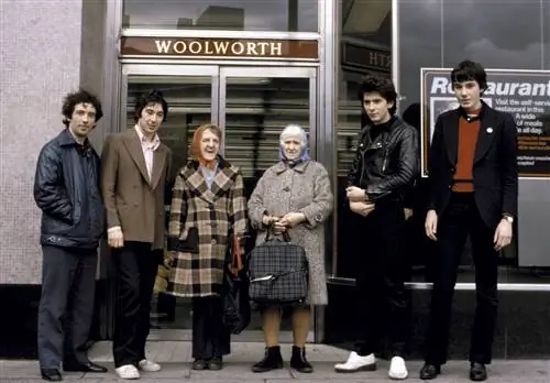 Пит Шелли, Стив Диггл, Стив Гарви и Джон Махер из группы The Buzzcocks позируют с двумя женщинами на фоне…