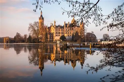 Рассвет в Шверинском замковом дворце (Schwerin Schloss), отражающемся в воде озера Шверинер-Зее. Объект всемирного наследия в Мекленбурге-Передней Померании, Германия Рассвет в Шверинском замковом дворце (Schwerin Schloss), отражающемся в воде озера Шверинер-Зее. Объект всемирного наследия в Мекленбурге-Передней Померании, Германия