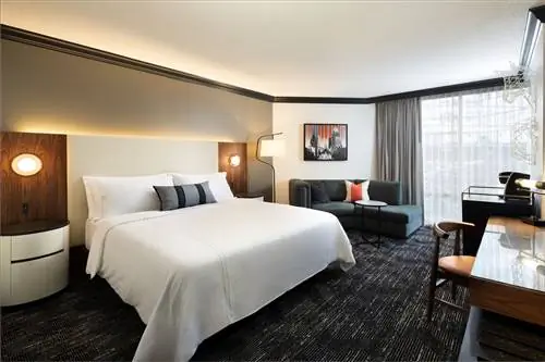 Кровать, черный диван и письменный стол в комнате Omni Downtown Austin с черным ковром.