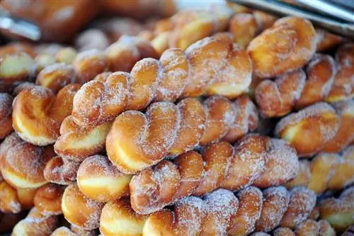 Стопка скрученных пончиков, посыпанных сахаром, в пекарне Стопка скрученных пончиков, посыпанных сахаром, в пекарне