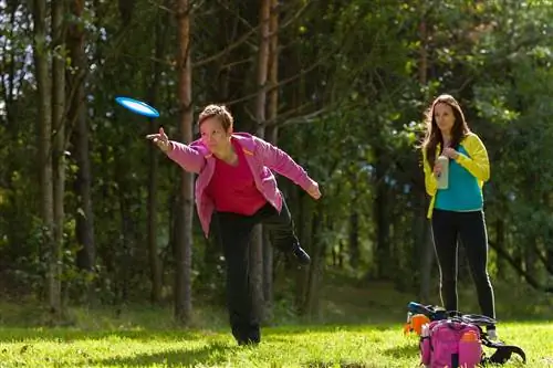 Женщина бросает диск, друг ждет на заднем плане