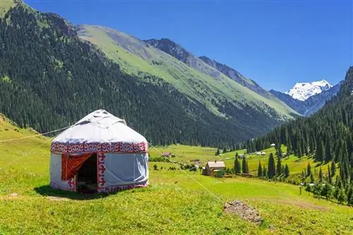 Красивый горный пейзаж с белой юртой, украшенной красным орнаментом, в Кыргызстане