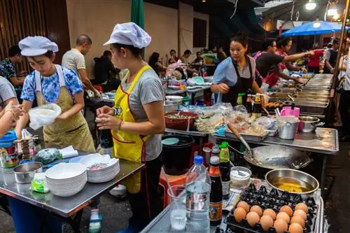 Повара готовят быстрые и дешевые блюда в большом продуктовом ларьке на улице в районе Силом.