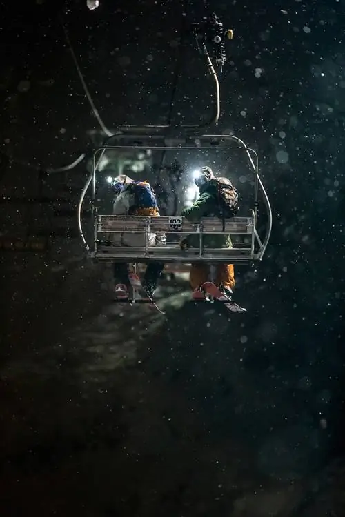 Крис Бенчетлер и Эрик Поллард наслаждаются безмятежностью снежной темной ночи в Нисеко, Япония, когда они поднимаются в кресле, чтобы продолжить ночное катание на лыжах.