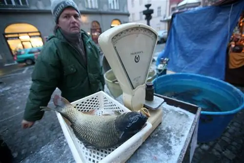 Продавец взвешивает карпа