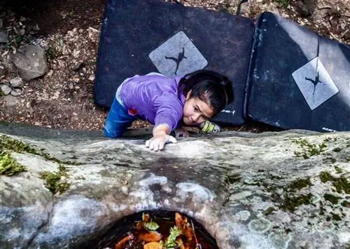 Вид сверху на молодую женщину, взбирающуюся на валун
