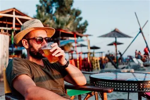 мужчина пьет пиво на пляже