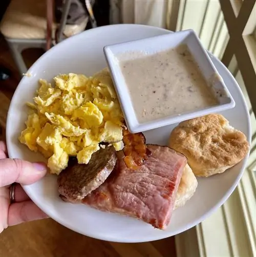 женщина держит белую тарелку с сосисками и печеньем - кукольная еда