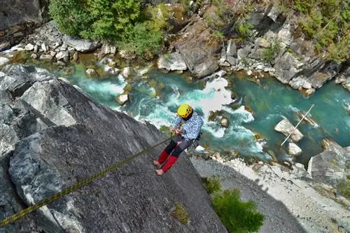Восхождение по величественному многоуровневому маршруту Star Chek к югу от Уистлера. Молодой человек спускается по красивому альпинистскому маршруту над дикой рекой, скалолазание в Британской Колумбии