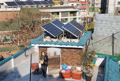 69-летний Вон Ён-Ае, житель деревни Сангол, несет цветочный горшок на крыше дома, где прохладная крыша и фотоэлектрические панели установлены для энергоэффективного ремонта в рамках Сеульской программы энергетического благосостояния. Среда, 9 ноября 2016 г. (Ли Джэ Вон/AP Images для C40)